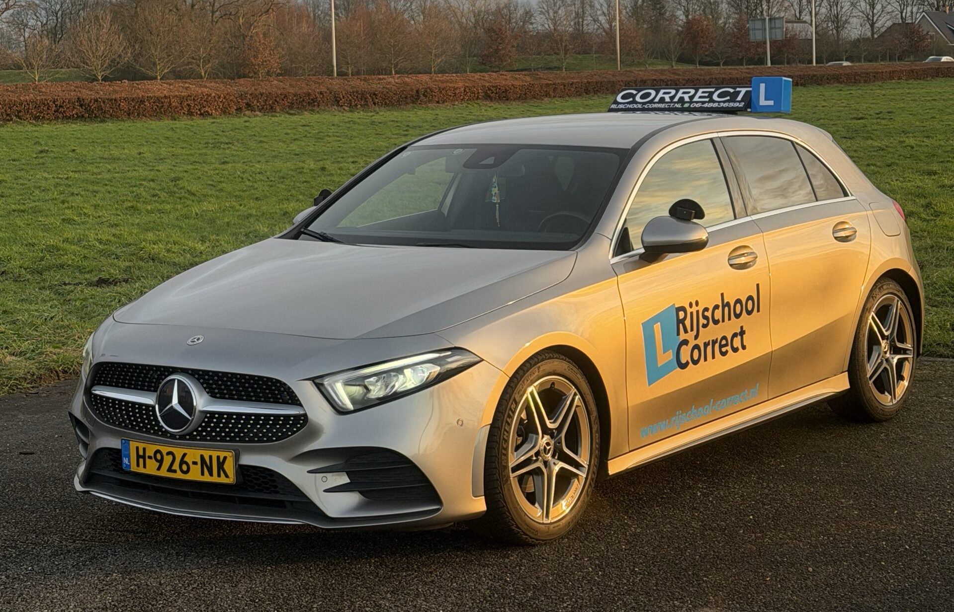 Mercedes Benz rijschoolauto op een schilderachtige weg bij zonsondergang